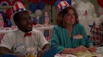 Movie still from “Something Wild” (1986), directed by Jonathan Demme – A man and a woman sitting at a table wearing patriotic hats; Medium shot, Low angle