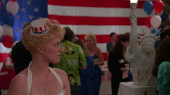 Movie still from “Something Wild” (1986), directed by Jonathan Demme – A woman wearing a patriotic hat in front of a crowd; Medium shot, Low angle