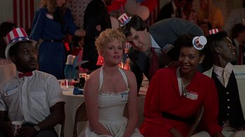 Movie still from “Something Wild” (1986), directed by Jonathan Demme – A woman in a white dress sitting next to a man in a red suit; Medium shot, High angle