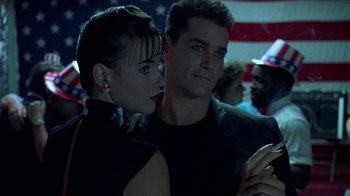 Movie still from “Something Wild” (1986), directed by Jonathan Demme – A man and a woman posing for a picture in front of an american flag; Close Up shot, Low angle
