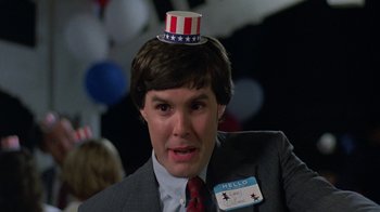 Movie still from “Something Wild” (1986), directed by Jonathan Demme – A man in a suit and tie wearing a paper hat; Close Up shot, Low angle