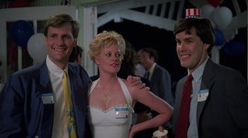 Movie still from “Something Wild” (1986), directed by Jonathan Demme – A woman in a white dress standing next to two men; Medium shot, Over the shoulder angle