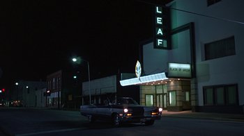 Movie still from “Something Wild” (1986), directed by Jonathan Demme – A car parked in front of a theater at night; Wide shot, Low angle