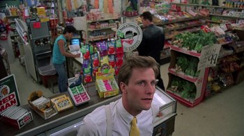 Movie still from “Something Wild” (1986), directed by Jonathan Demme – A man in a grocery store standing in front of the cash register; Medium shot, Low angle