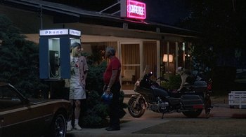 Movie still from “Something Wild” (1986), directed by Jonathan Demme – A couple of people standing on the side of a road; Wide shot, Low angle