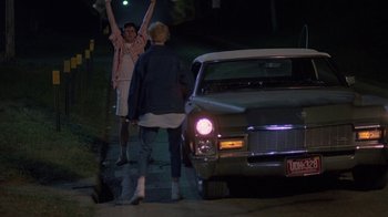 Movie still from “Something Wild” (1986), directed by Jonathan Demme – A couple of people standing next to a car; Wide shot, Low angle