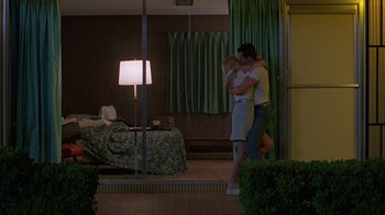 Movie still from “Something Wild” (1986), directed by Jonathan Demme – A man and a woman embracing in a hotel room; Wide shot, Low angle