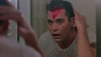 Movie still from “Something Wild” (1986), directed by Jonathan Demme – A man is looking into a mirror with a red spot on his forehead; Close Up shot, Over the shoulder angle