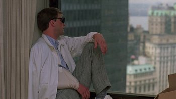 Movie still from “Something Wild” (1986), directed by Jonathan Demme – A man sitting on a window sill in front of a large window; Medium shot, Low angle