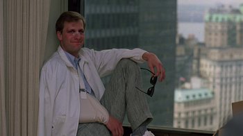 Movie still from “Something Wild” (1986), directed by Jonathan Demme – A man sitting on the ground in front of a window; Medium shot, Low angle
