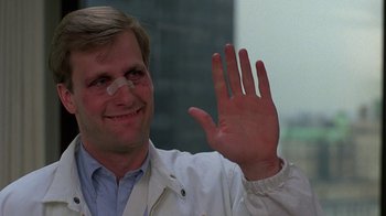 Movie still from “Something Wild” (1986), directed by Jonathan Demme – A man in a white lab coat waving at the camera; Close Up shot, Over the shoulder angle