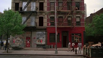 Movie still from “Something Wild” (1986), directed by Jonathan Demme – A group of people walking down a street near a building; Extreme Wide shot, Low angle
