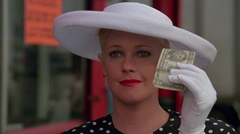 Movie still from “Something Wild” (1986), directed by Jonathan Demme – A woman in a white hat holding a dollar bill in front of her face; Close Up shot, Over the shoulder angle