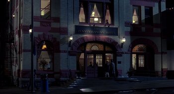 Movie still from “Groundhog Day” (1993), directed by Harold Ramis – People are standing in front of the entrance to the pennsylvania hotel at night; Extreme Wide shot, High angle