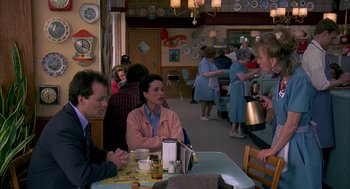 Movie still from “Groundhog Day” (1993), directed by Harold Ramis – A group of people sitting at a table in a restaurant; Medium shot, Over the shoulder angle
