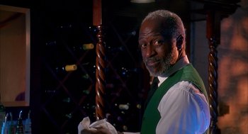 Movie still from “Groundhog Day” (1993), directed by Harold Ramis – A man in a green vest and white shirt holding a wooden pole; Medium shot, Low angle