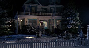 Movie still from “Groundhog Day” (1993), directed by Harold Ramis – A house that has a picket fence in front of it at night; Extreme Wide shot, High angle