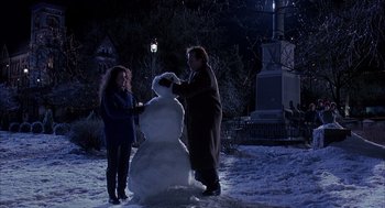 Movie still from “Groundhog Day” (1993), directed by Harold Ramis – Two people standing next to a snowman in the snow; Medium shot, Low angle