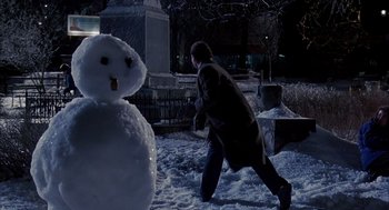 Movie still from “Groundhog Day” (1993), directed by Harold Ramis – A man walking in the snow next to a snowman; Medium shot, Low angle