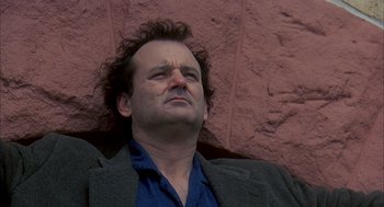 Movie still from “Groundhog Day” (1993), directed by Harold Ramis – A person laying on the ground near a brick wall; Close Up shot, Low angle