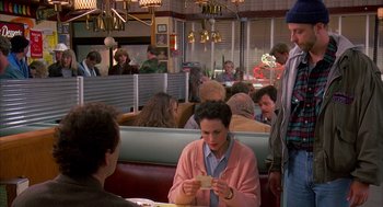 Movie still from “Groundhog Day” (1993), directed by Harold Ramis – A group of people sitting at a table in a restaurant; Medium shot, Over the shoulder angle