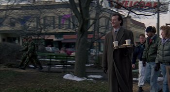 Movie still from “Groundhog Day” (1993), directed by Harold Ramis – A man holding a tray of food and a cup of coffee; Wide shot, Low angle