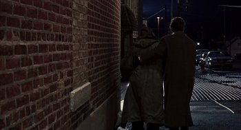 Movie still from “Groundhog Day” (1993), directed by Harold Ramis – Two men in coats are standing in the dark; Wide shot, Over the shoulder angle