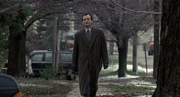 Movie still from “Groundhog Day” (1993), directed by Harold Ramis – A man in a suit and tie walking down a sidewalk; Wide shot, Low angle