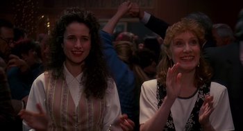 Movie still from “Groundhog Day” (1993), directed by Harold Ramis – Two women are smiling and holding their hands in the air; Medium shot, Over the shoulder angle