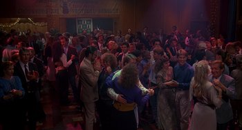 Movie still from “Groundhog Day” (1993), directed by Harold Ramis – A group of people standing around each other in a room; Wide shot, High angle