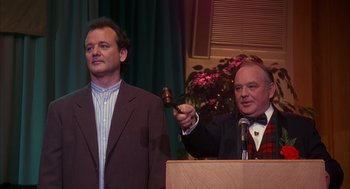 Movie still from “Groundhog Day” (1993), directed by Harold Ramis – A man holding a gavel in front of another man; Medium shot, Over the shoulder angle