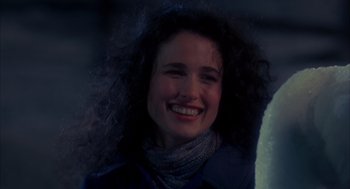 Movie still from “Groundhog Day” (1993), directed by Harold Ramis – A woman with curly black hair smiling for the camera; Close Up shot, Over the shoulder angle