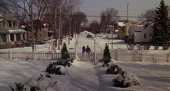 Movie still from “Groundhog Day” (1993), directed by Harold Ramis – Two people standing in the snow next to a gate; Extreme Wide shot, High angle