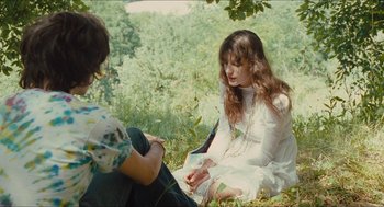 Movie still from “Something in the Air” (2012), directed by Olivier Assayas – Two women sitting on the ground in the grass; Medium shot, Over the shoulder angle