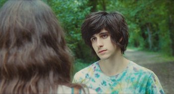 Movie still from “Something in the Air” (2012), directed by Olivier Assayas – A young man with long black hair is looking at a young woman; Close Up shot, Over the shoulder angle
