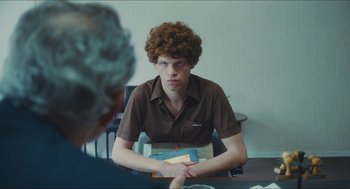 Movie still from “Something in the Air” (2012), directed by Olivier Assayas – A young man sitting in front of an older man; Medium shot, Over the shoulder angle