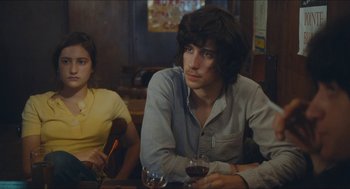 Movie still from “Something in the Air” (2012), directed by Olivier Assayas – A man and a woman sitting at a table with a glass of red wine; Medium shot, Over the shoulder angle