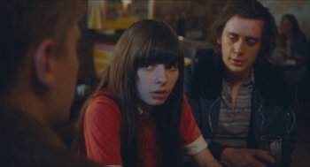 Movie still from “Something in the Air” (2012), directed by Olivier Assayas – A woman with long hair sitting next to two men; Medium shot, Over the shoulder angle