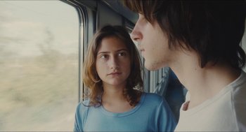 Movie still from “Something in the Air” (2012), directed by Olivier Assayas – A man and a woman looking out of a train window; Close Up shot, Over the shoulder angle