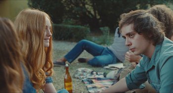 Movie still from “Something in the Air” (2012), directed by Olivier Assayas – A group of people sitting on the grass; Medium shot, Over the shoulder angle