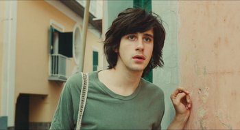 Movie still from “Something in the Air” (2012), directed by Olivier Assayas – A young man with long hair and a green shirt; Close Up shot, Low angle