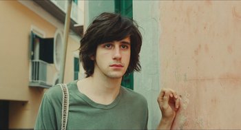 Movie still from “Something in the Air” (2012), directed by Olivier Assayas – A young man with long hair and a green shirt; Close Up shot, Low angle