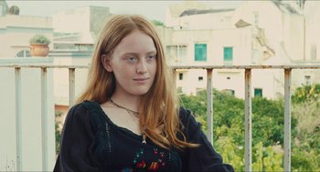 Movie still from “Something in the Air” (2012), directed by Olivier Assayas – A girl with long red hair wearing a black shirt; Close Up shot, Over the shoulder angle