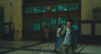 Movie still from “Something in the Air” (2012), directed by Olivier Assayas – A man standing in front of a building at night; Wide shot, Low angle