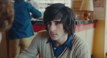 Movie still from “Something in the Air” (2012), directed by Olivier Assayas – A young man with long hair and a mustache; Close Up shot, Over the shoulder angle