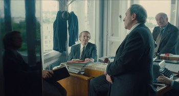 Movie still from “Something in the Air” (2012), directed by Olivier Assayas – Two men sitting at a desk in front of a window; Medium shot, Over the shoulder angle