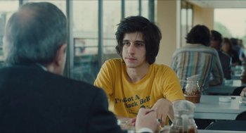 Movie still from “Something in the Air” (2012), directed by Olivier Assayas – A man sitting at a table in front of another man; Close Up shot, Over the shoulder angle
