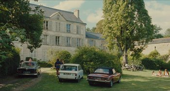 Movie still from “Something in the Air” (2012), directed by Olivier Assayas – Two cars parked in front of an old house; Extreme Wide shot, Low angle