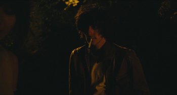 Movie still from “Something in the Air” (2012), directed by Olivier Assayas – A person with a cigarette in their mouth; Medium shot, Over the shoulder angle