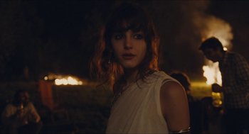 Movie still from “Something in the Air” (2012), directed by Olivier Assayas – A woman in a white shirt is standing in a field at night; Close Up shot, Over the shoulder angle